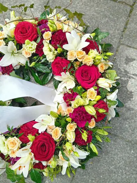 Rundgesteckter Trauerkranz mit roten Rosen und Nelken